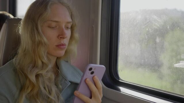 tired blonde woman, on the train, chatting on the phone, slow motion