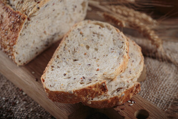 Sliced fresh baked whole grain bread with oats, flax seeds and sesame seeds on rustic wooden board. Bakery products