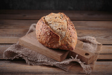 Fresh baked whole grain bread with oats, flax seeds and sesame seeds on rustic wooden board. Bakery products