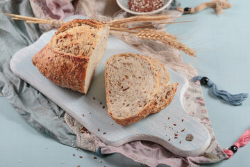 Sliced fresh baked whole grain bread with flax seeds and sesame seeds on light blue board. Bakery products