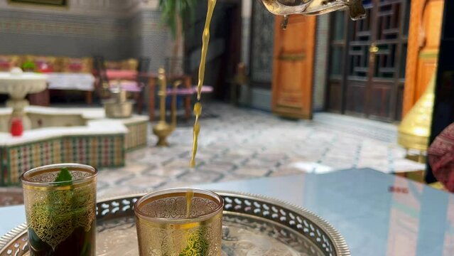 Man pouring mint tea into a Moroccan glasses