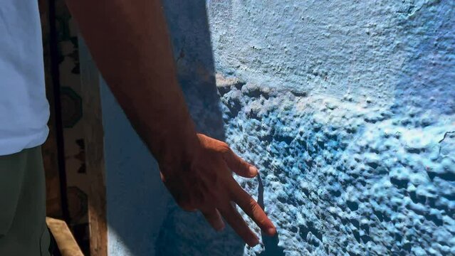 Man walking and touching the wall in Chefchaouen