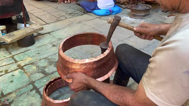 Man manually processing metal pots in the old Medina of Fes