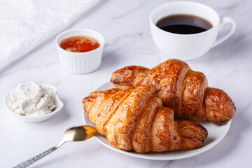 Fresh sweet croissants with cottage cheese and apricot jam for breakfast. Continental breakfast on a white table
