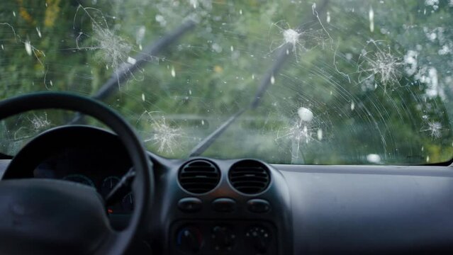 a broken car windshield and falling hail during a natural disaster storm