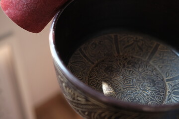 Women in a blue scarf using singing copper bowl. Yoga, relaxation and meditation. Sound therapy, alternative medicine