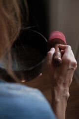 Women in a blue scarf using singing copper bowl. Yoga, relaxation and meditation. Sound therapy, alternative medicine