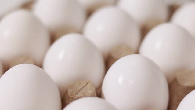 White chicken eggs in a cardboard box. Fresh raw eggs in a paper egg container for store and shop. egg tray with eggs on white table background. Top view. preparation to easter holiday.