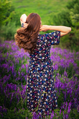 A girl in a purple dress on a background of blue flowers