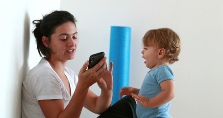 Candid child infant giving smartphone to mother