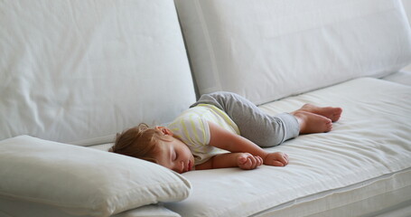 Candid baby sleeping on sofa in the afternoon nap. Cute infant toddler asleep
