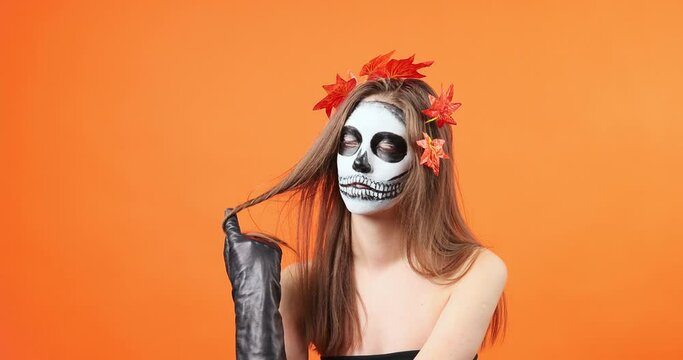 Halloween makeup, almost Santa Muerte or Mexican sugar skull, makeup. The girl is playing with her hair. Slow motion.