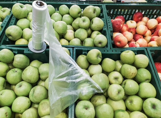 I buy green apples in the supermarket. Juicy apple in the field of the farmer's market. Next to the apples is a roll of packing bags.