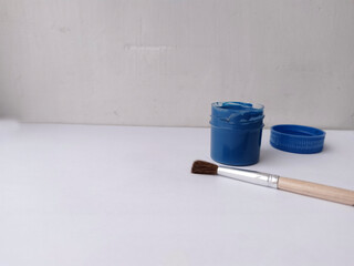 Brush and jar with blue paint on a white background. The paint is open. Everything for drawing....