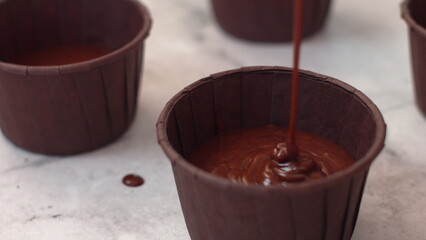 Cupcake mold is filled with chocolate dough, close-up. Confectionery kitchen, cupcake preparation, production process. Chocolate dough is poured into cupcakes molds