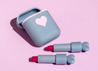 red lipstick in a cute gray case on a pink background with hard shadows