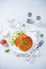 Fresh prepared schnitzel in a plate with fresh cucumber slices