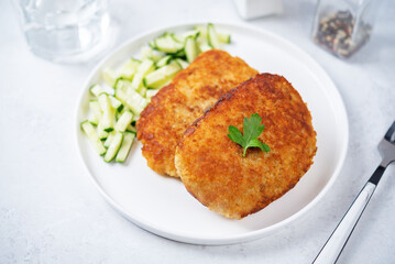 Fresh prepared schnitzel in a plate with fresh cucumber slices
