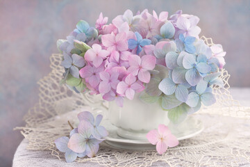 Colorful bouquet with blue, pink and green hydrangea in a cup on the table. Postcard for the holidays.