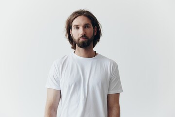 Portrait of a man with a black thick beard and long hair in a white T-shirt on a white isolated...