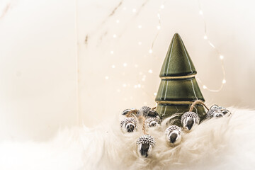 a figurine of a ceramic Christmas tree with silver Christmas acorns. Background photo of a greeting card