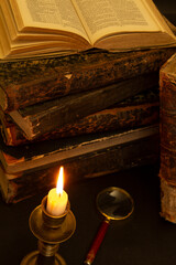 old books on the table, reading by candlelight, magnifier	