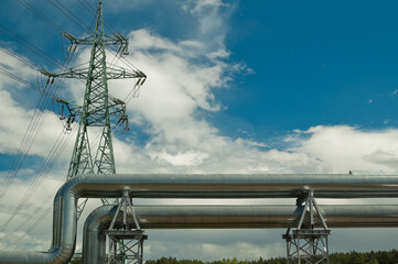 pipeline and power lines on the background of blue sky and clouds