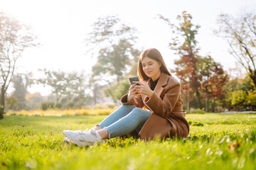 Pretty woman with smartphone having a good time in autumn weekend. People, lifestyle, relaxation and vacations concept. 