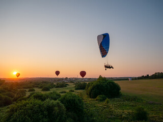 Obraz premium Colorful air balloon is flying in free flight over the field. Bird's-eye view. Multicolored balloon in the sky at sunset