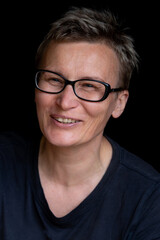 Fototapeta premium Portrait of caucasian woman with short haircut and black-rimmed glasses on black background, close-up. Emotions on face. High quality photo