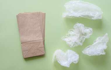 Paper eco-friendly bags next to plastic bags on a green background. The concept of refusing to use plastic to save the environment.