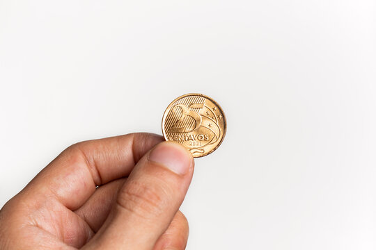 Hand holding Brazilian Real Twenty-Five Centavos coin on white background