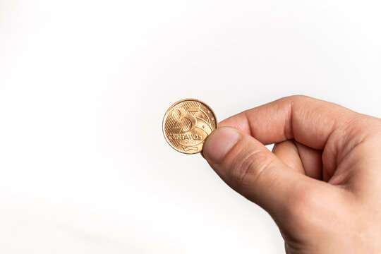 Hand holding Brazilian Real Twenty-Five Centavos coin on white background