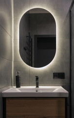 Front view of modern oval shape bathroom mirror with back light - obrazy, fototapety, plakaty