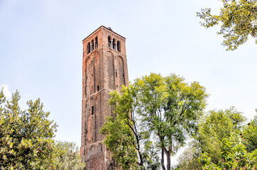 Murano, Italy - July 7, 2022: A bell tower seen through the trees in Murano Italy
