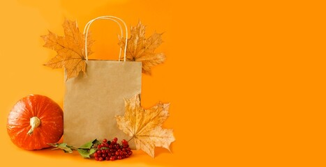 Banner on orange background ecological paper bag for seasonal and holiday shopping.  The concept of autumn sales, discounts for the Halloween holiday.  Space for copy text.