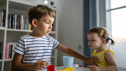 Obraz premium One boy trying to stop his little sister to take his toys siblings