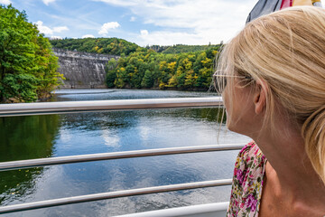 beautiful girl looking at dam at String of Lights on top of a boat traveling through lake Rursee,...