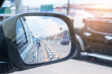 Cars run through the street from the Gray car's side view mirror.  city beside. Road Car Rear View Mirror Motion Blur Background (Vintage Style)