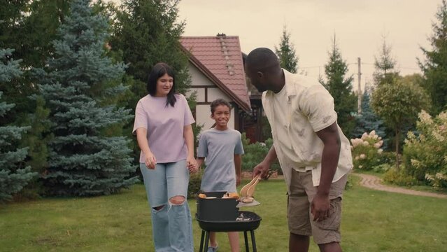 An African dad cooks krill vegetables for his multi-ethnic family.Multiracial Family,Mixed Race,Diverse People,Multiethnic Relations