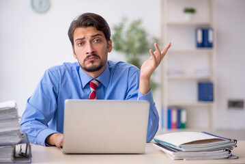 Young male employee unhappy with excessive work in the office