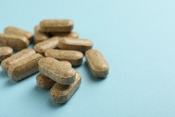 Dietary supplement pills on light blue background, closeup. Space for text