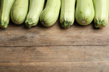 Raw green zucchinis on wooden table, above view. Space for text