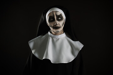 Portrait of scary devilish nun on black background, space for text. Halloween party look