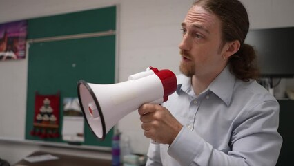 Angry teacher shouting in classroom into megaphone loudhailer, bullhorn, trying to make students listen. Concept of teacher frustration with class.