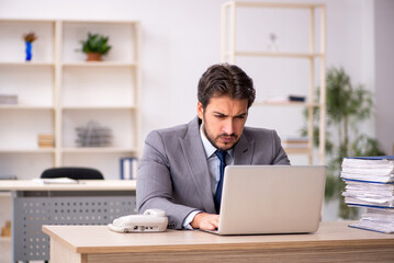 Young male employee and too much work in the office