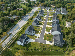 Aerial top down view of new single family home neighborhood with drive ways off the main street
