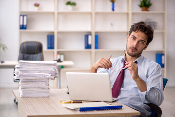 Naklejka premium Young male employee and too much work in the office