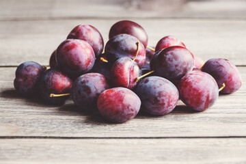 Plums in a pile on wooden table, harvested plum fruits in autumn, copy space