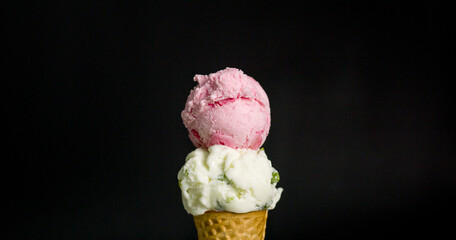 Close-up of ice cream cones in two flavors coconut milk and strawberry on black background.